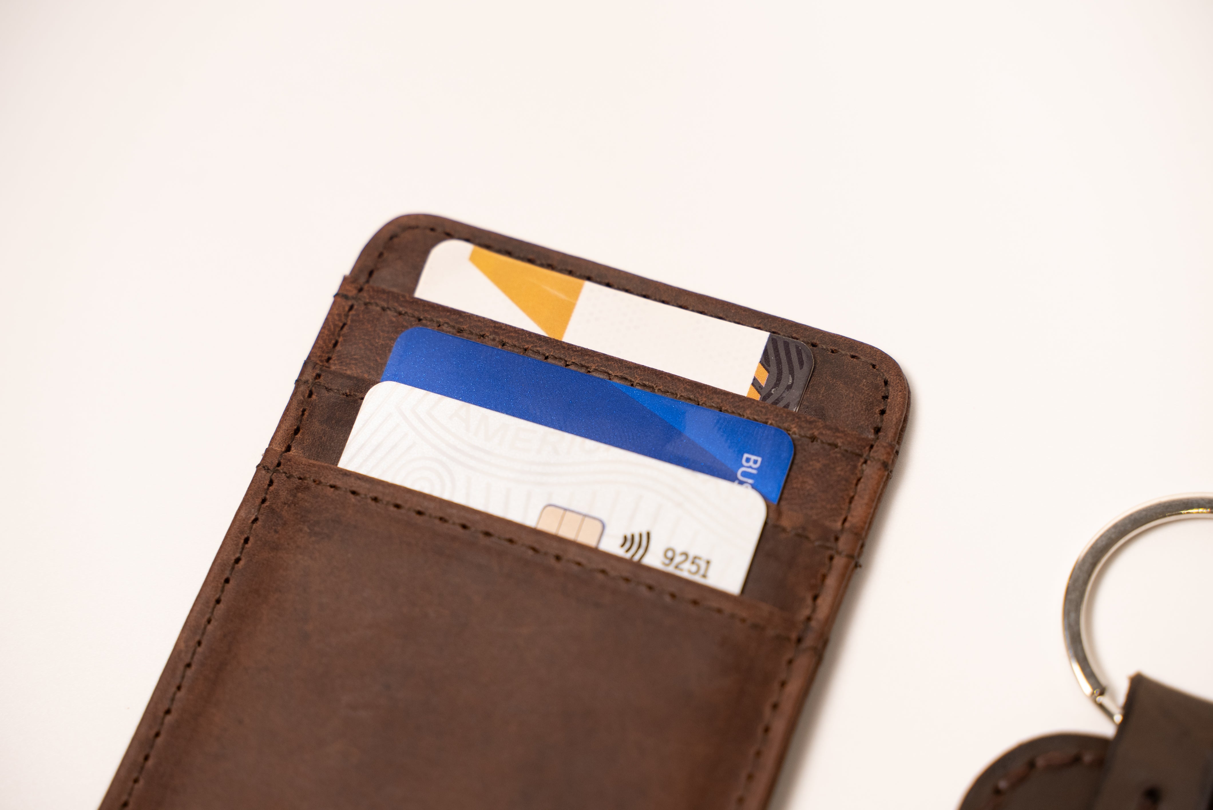 Brown leather wallet with cards and keychain on a light background