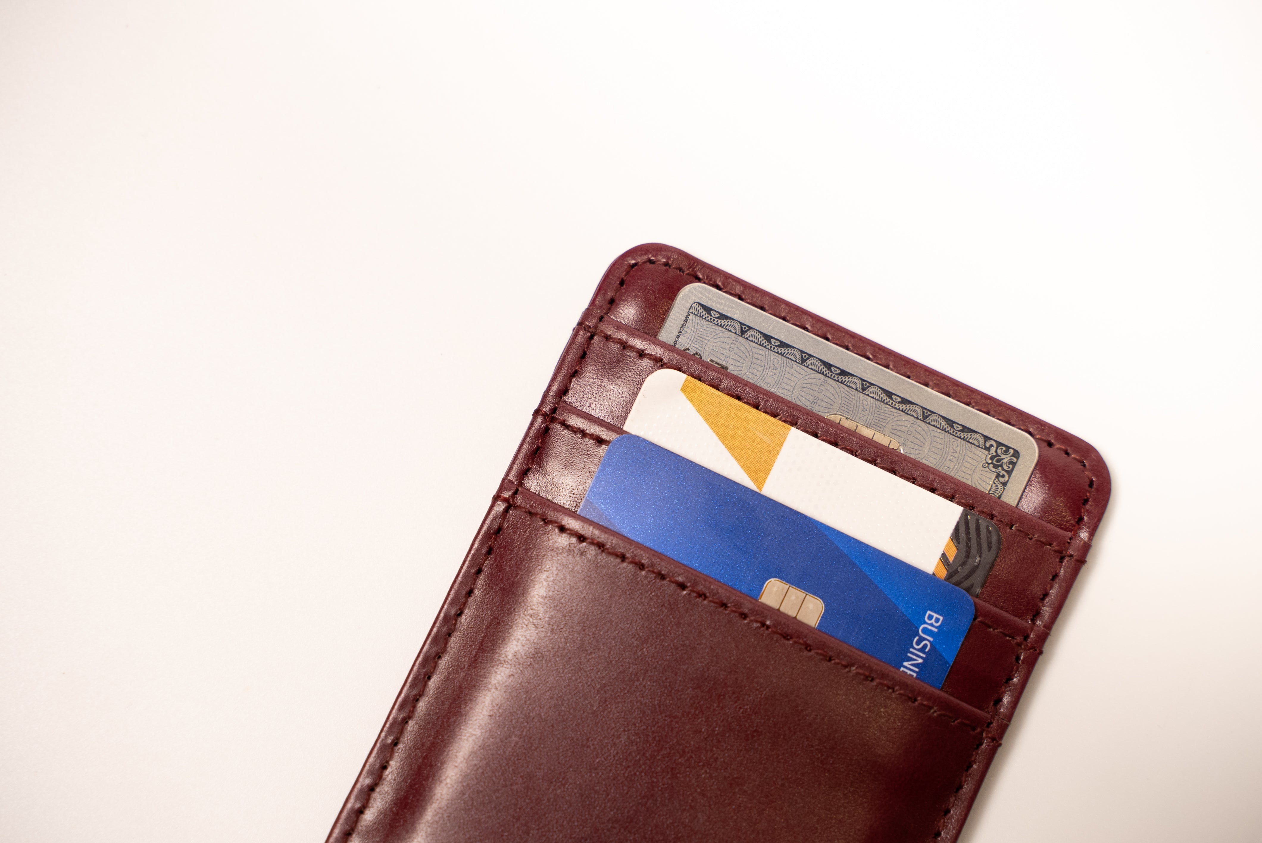 Brown leather wallet with cards and money on a light beige background
