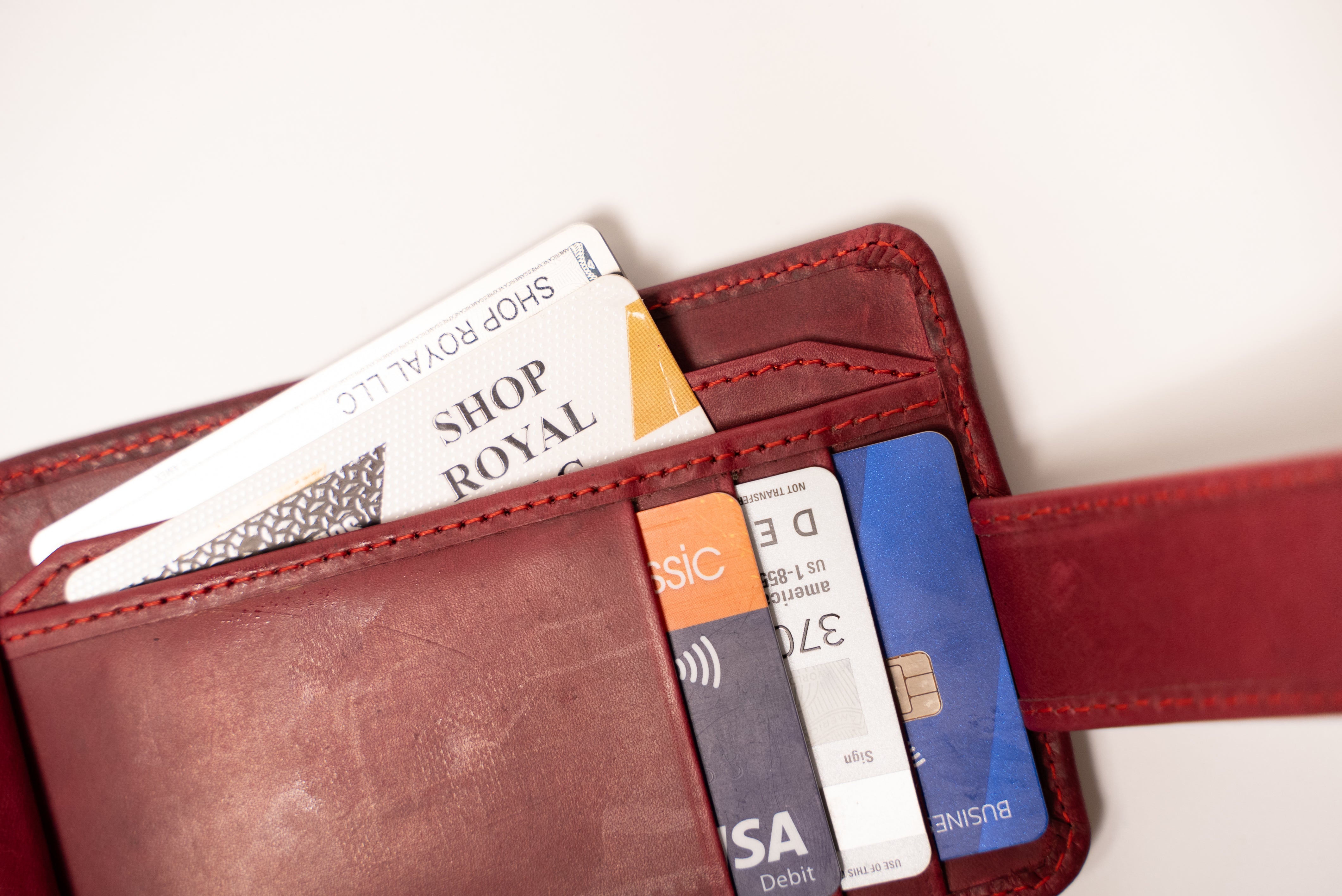 Red wallet with various cards including a Shop Royal card on a white background
