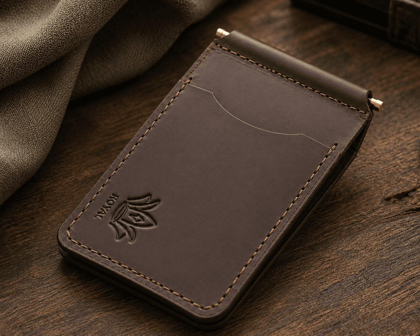 Brown money clip wallet on a wooden table beside a coffee cup
