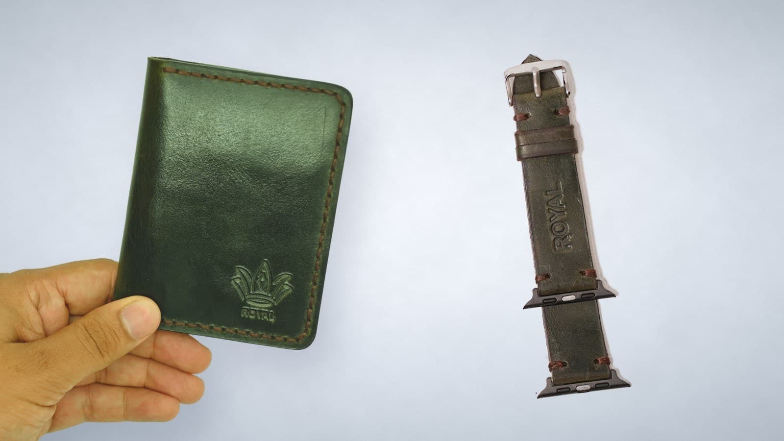 A hand holding a green ROYAL leather card holder beside an olive green leather watch strap