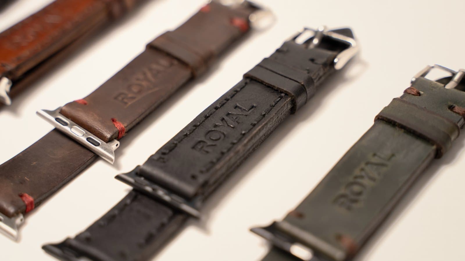 Close-up of ROYAL leather watch bands showing the embossed logo, edge finish and stitching