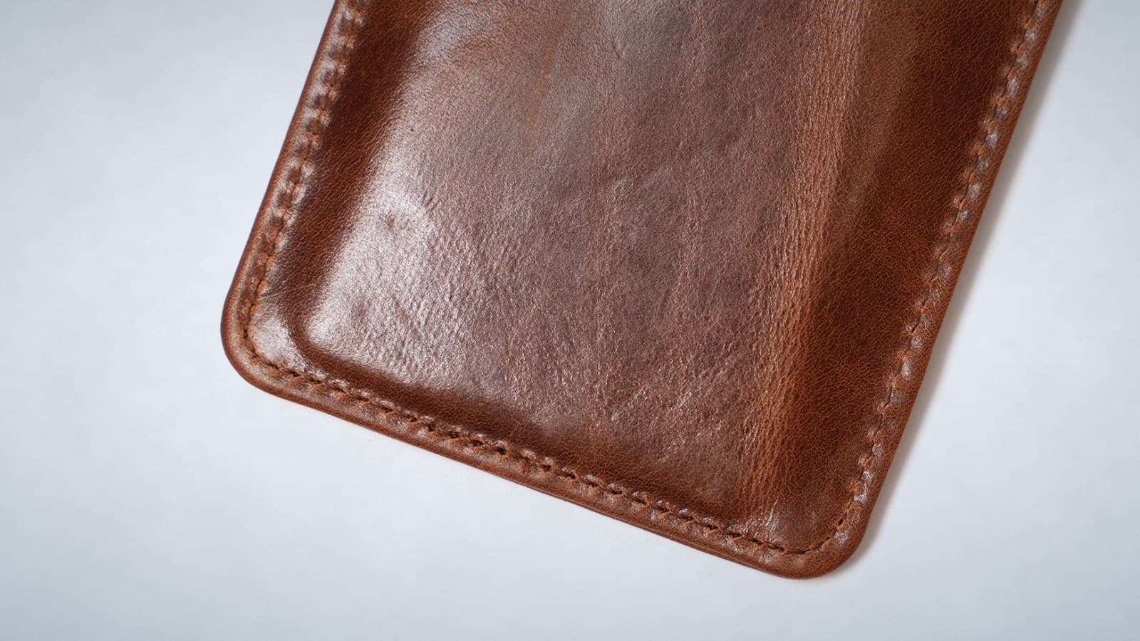 Close-up of glossy cognac ROYAL leather with natural colour variation and a stitched edge