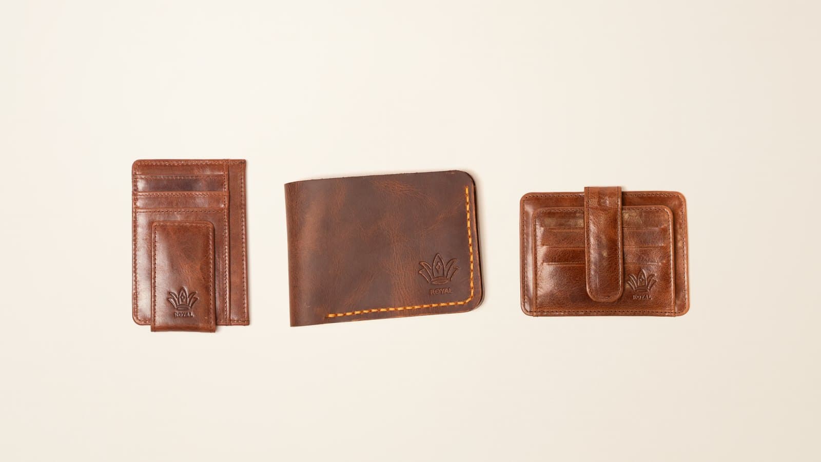 Three ROYAL leather wallet styles side by side: a front pocket wallet, a bifold and a card holder, on an ivory linen backdrop