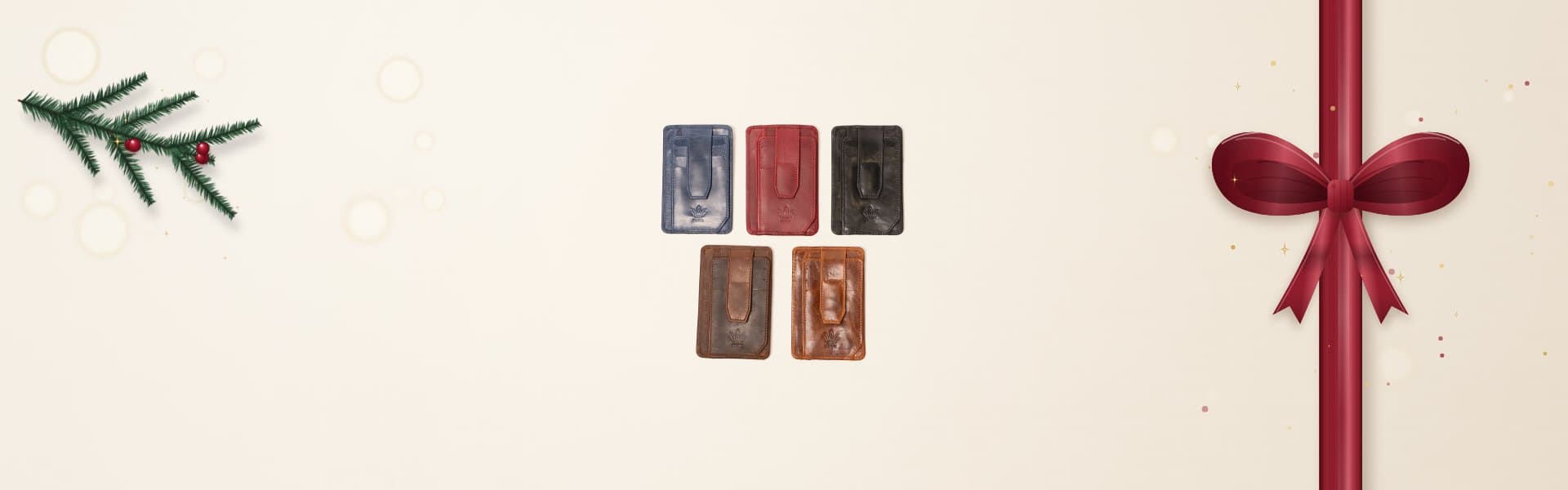 Three ROYAL leather card holders in dark brown, burgundy and cognac on a warm cream surface