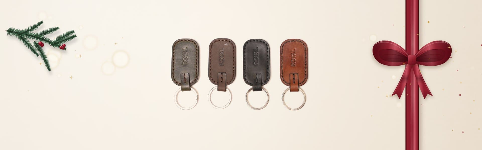 Four ROYAL leather keychains in olive, brown, black and tan with silver split rings on a warm cream surface