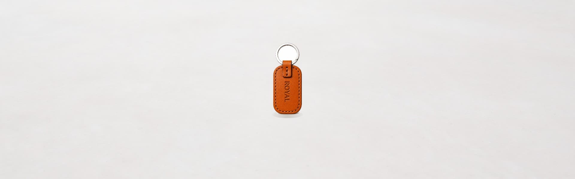 ROYAL leather keychain on a light stone backdrop