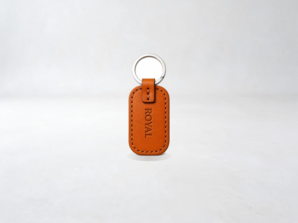 ROYAL leather keychain on a light stone backdrop