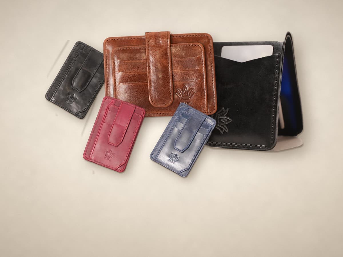 ROYAL minimalist carry on a warm cream surface: magnetic card holders in cognac, dark brown and burgundy, a cognac signature card holder and a black front pocket wallet