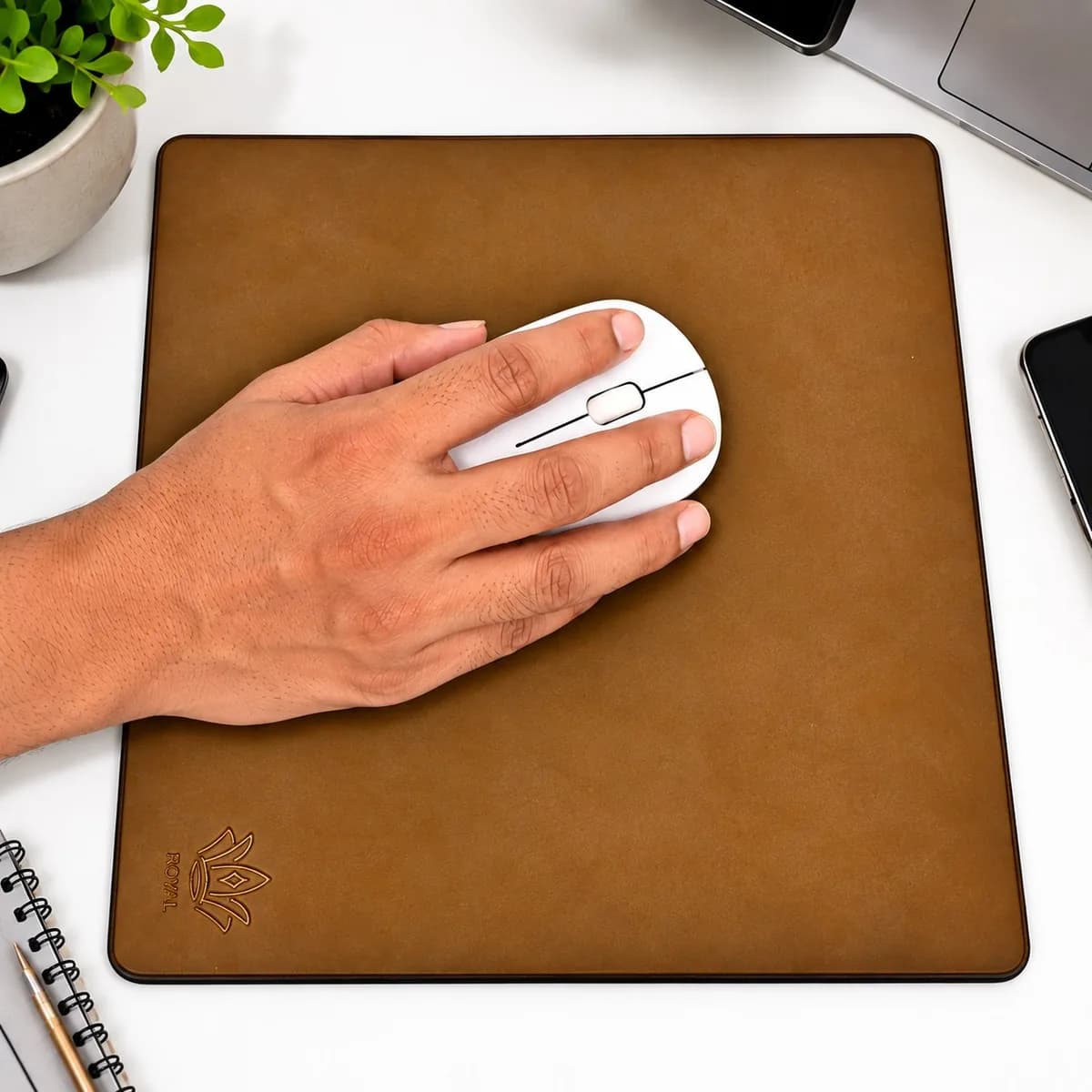 Dark brown ROYAL leather mouse pad in use on a white desk next to a laptop, notebook and plant