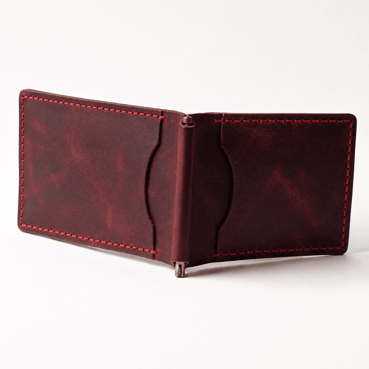 Burgundy money clip wallet opened flat, brass spring clip and card slots, angled view