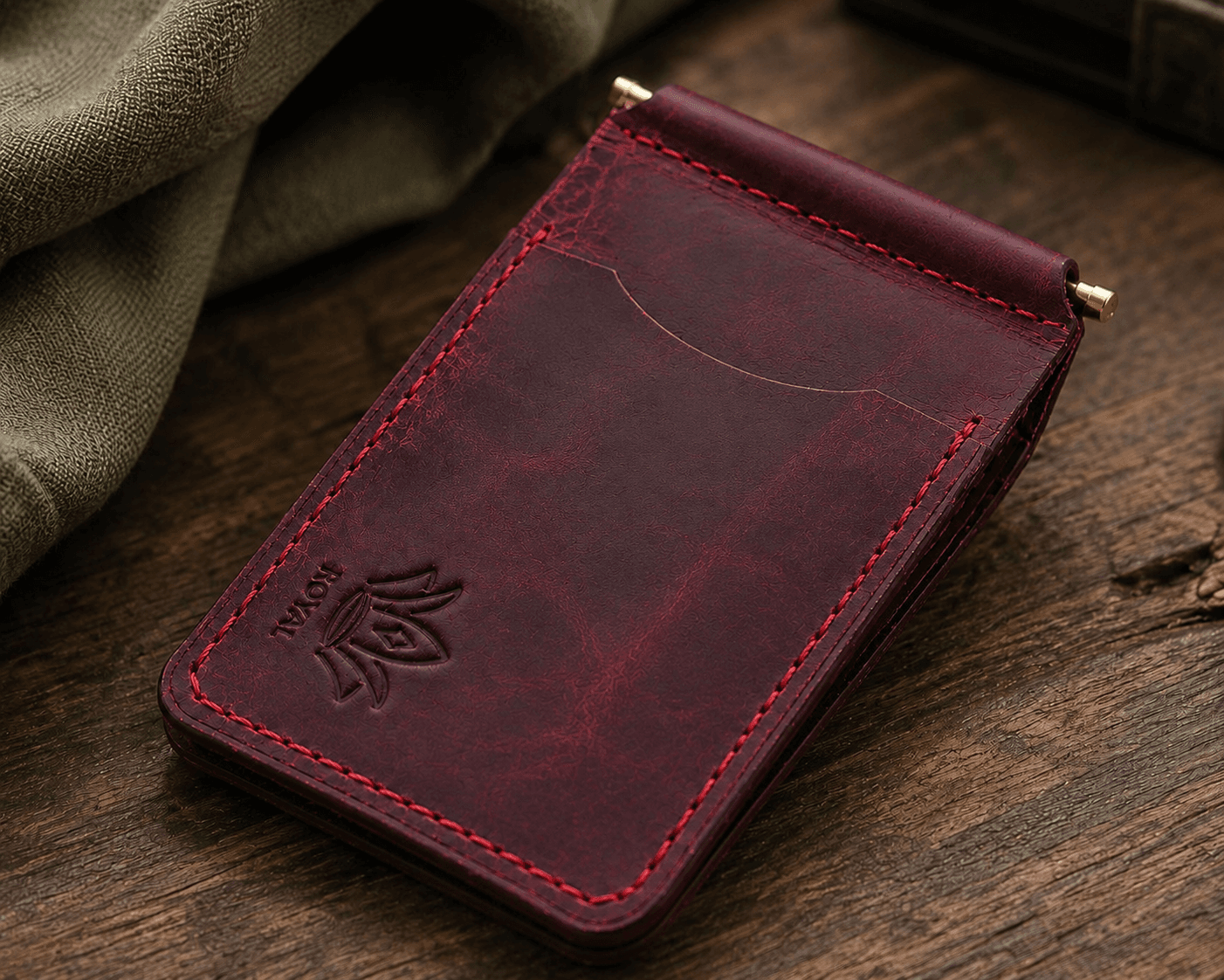 Burgundy money clip wallet on a wooden table beside a coffee cup