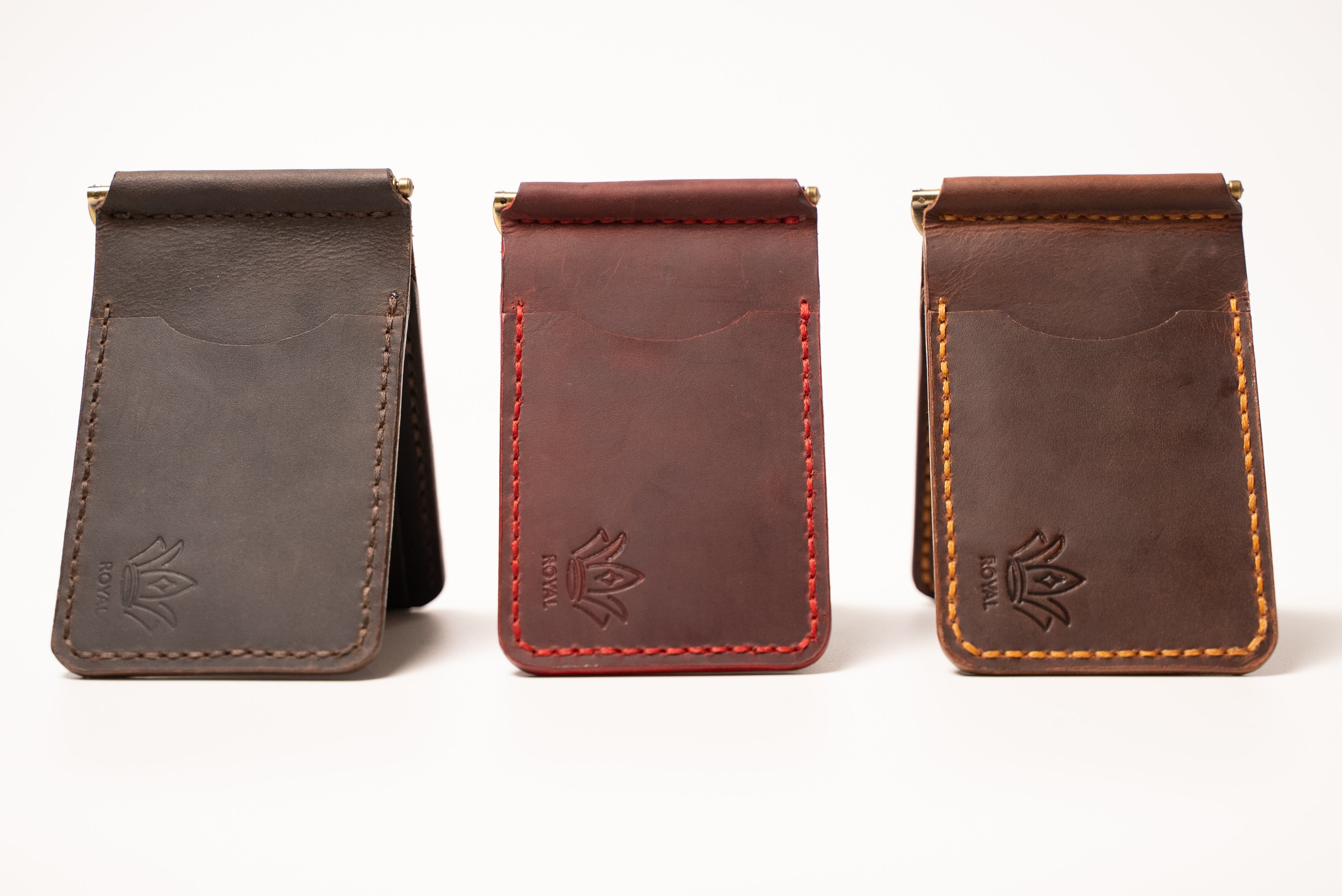 Three leather money clip wallets in different colors on a white background